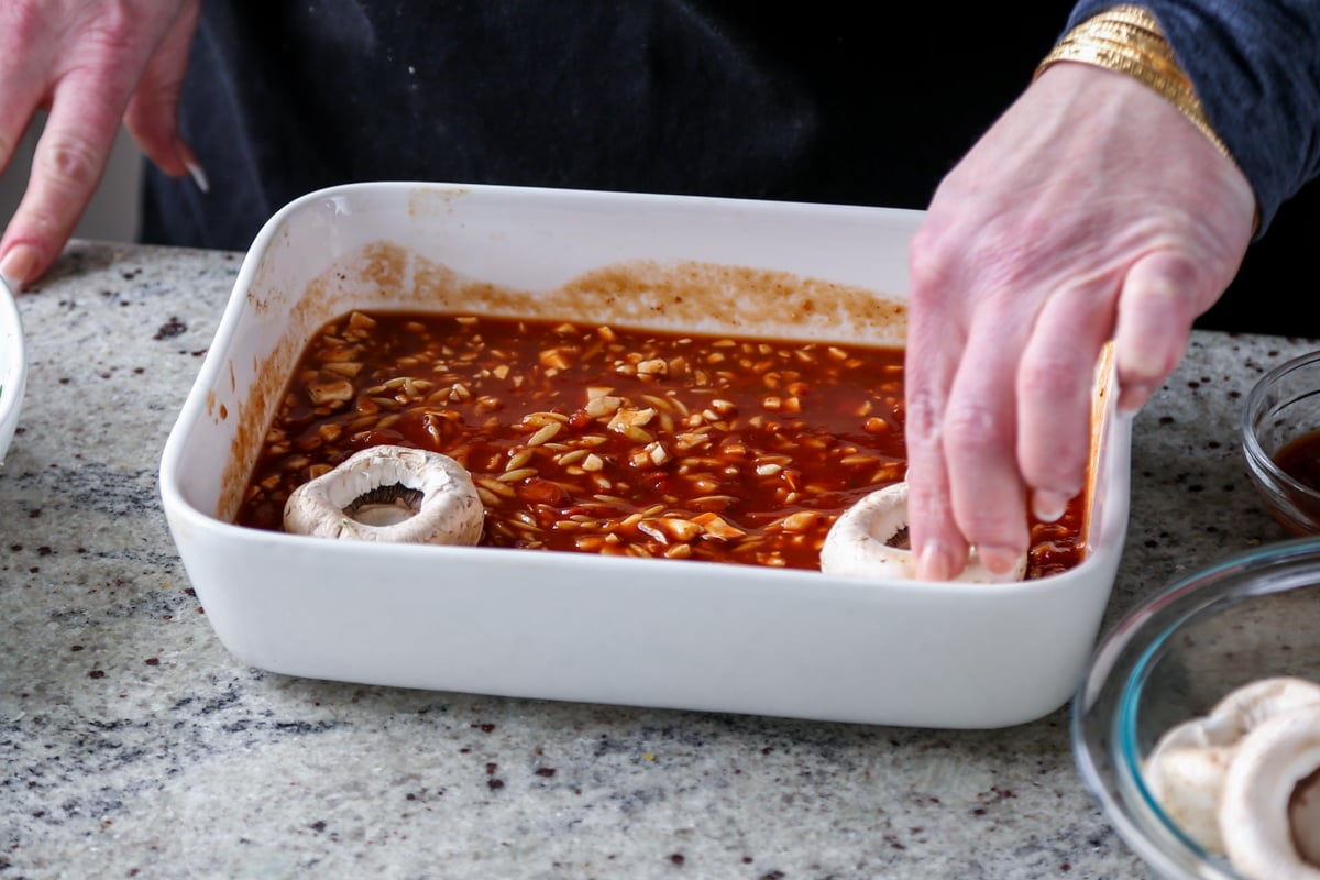 adding mushrooms to the pan of pasta