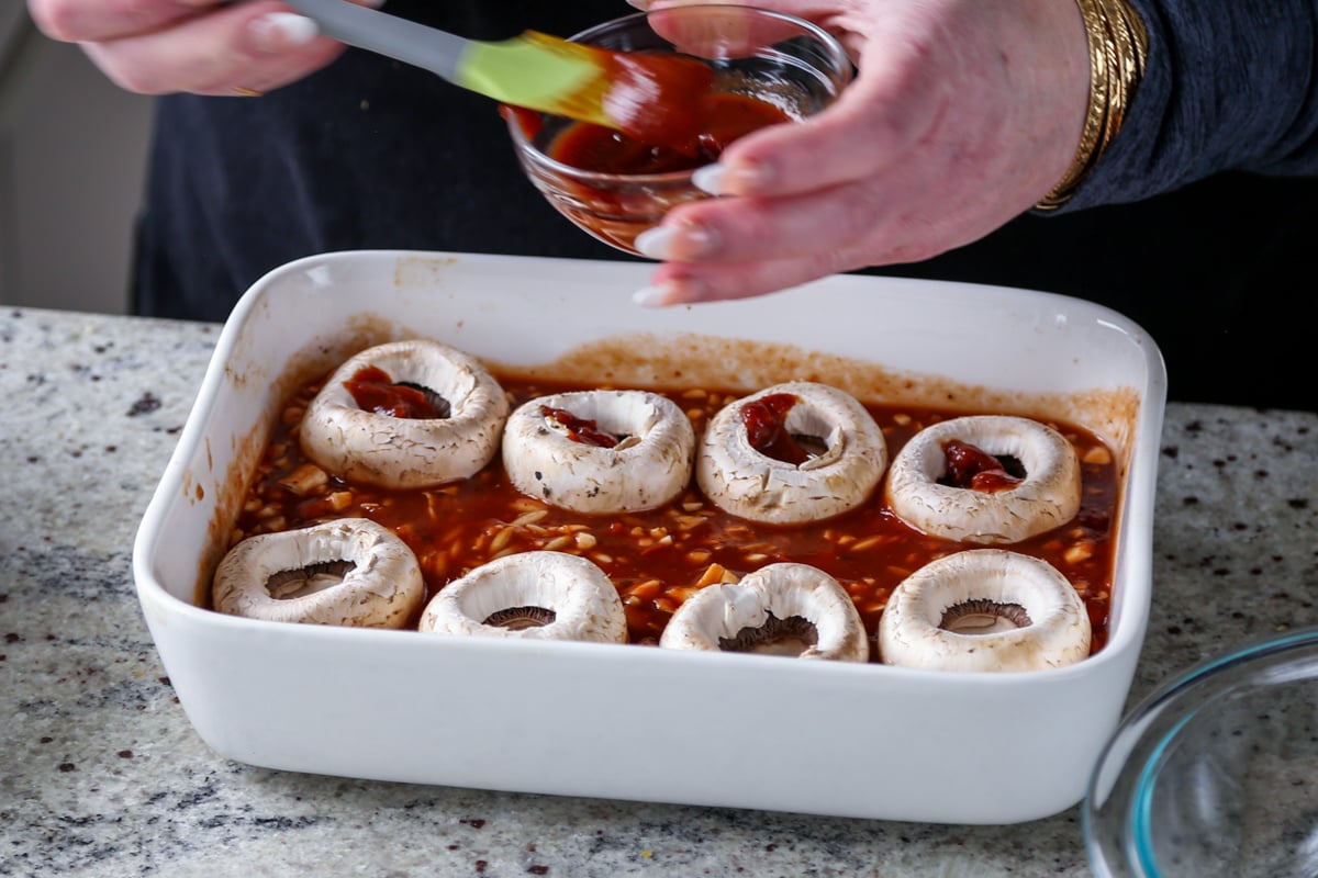 brushing marinara onto the mushrooms