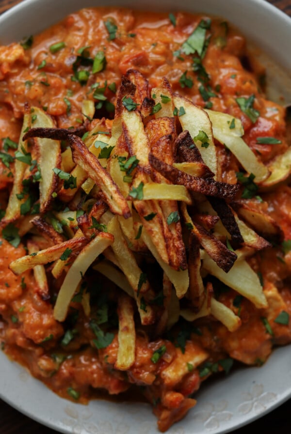 bowl of boti topped with crispy salli potatoes