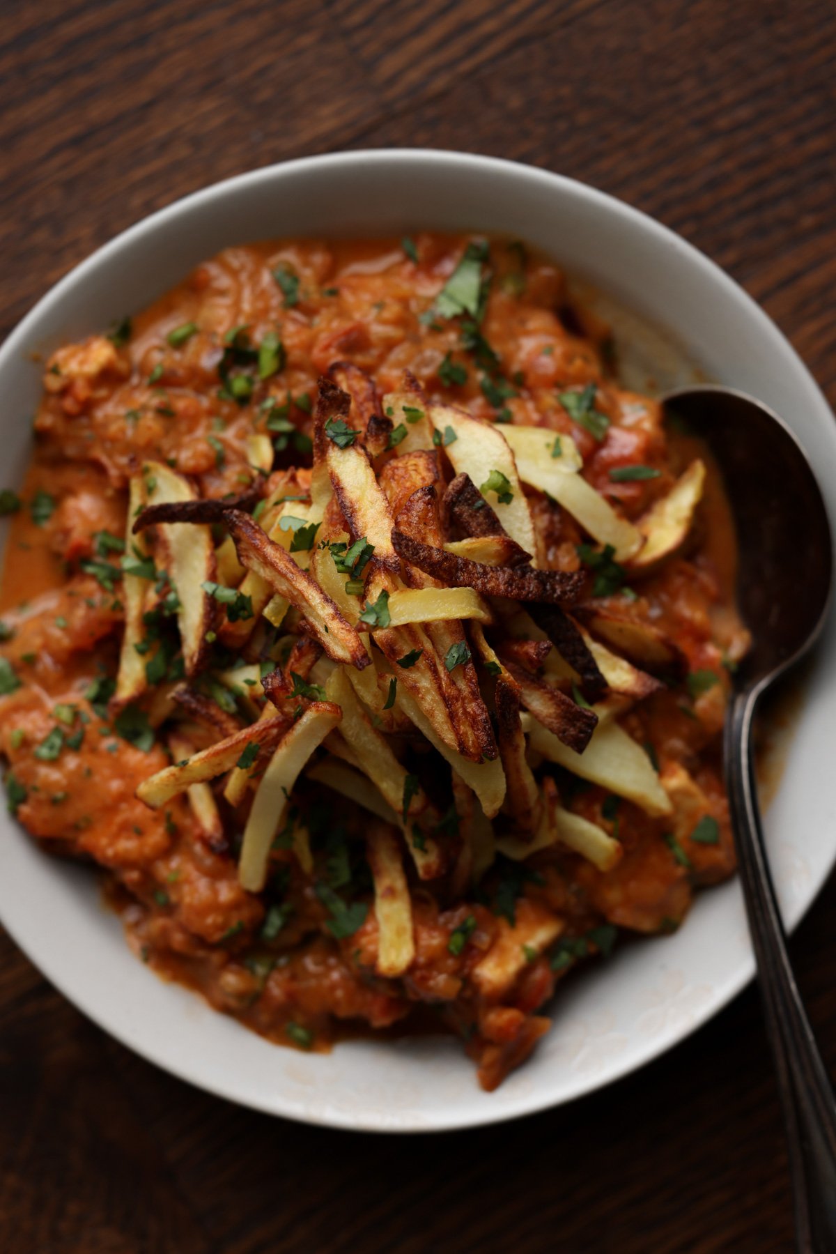 bowl of boti topped with crispy salli potatoes