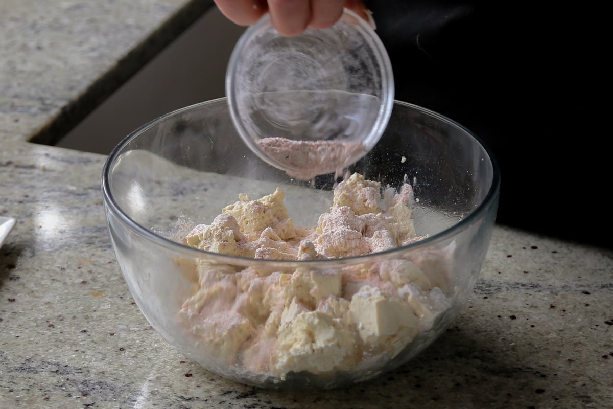 sprinkling the cornstarch and spices over the bowl of tofu