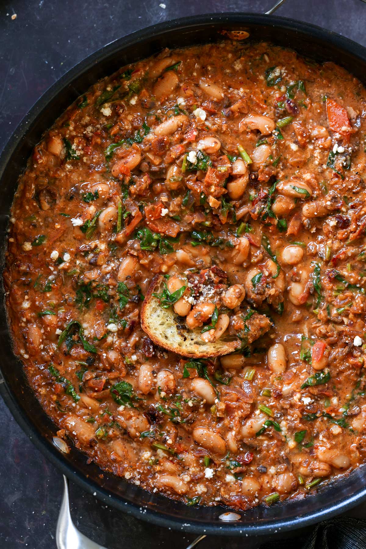 dipping toasted sourdough into vegan sausage pasta sauce in the pan