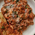 vegan sausage pasta sauce on a plate with toasted sourdough on the side