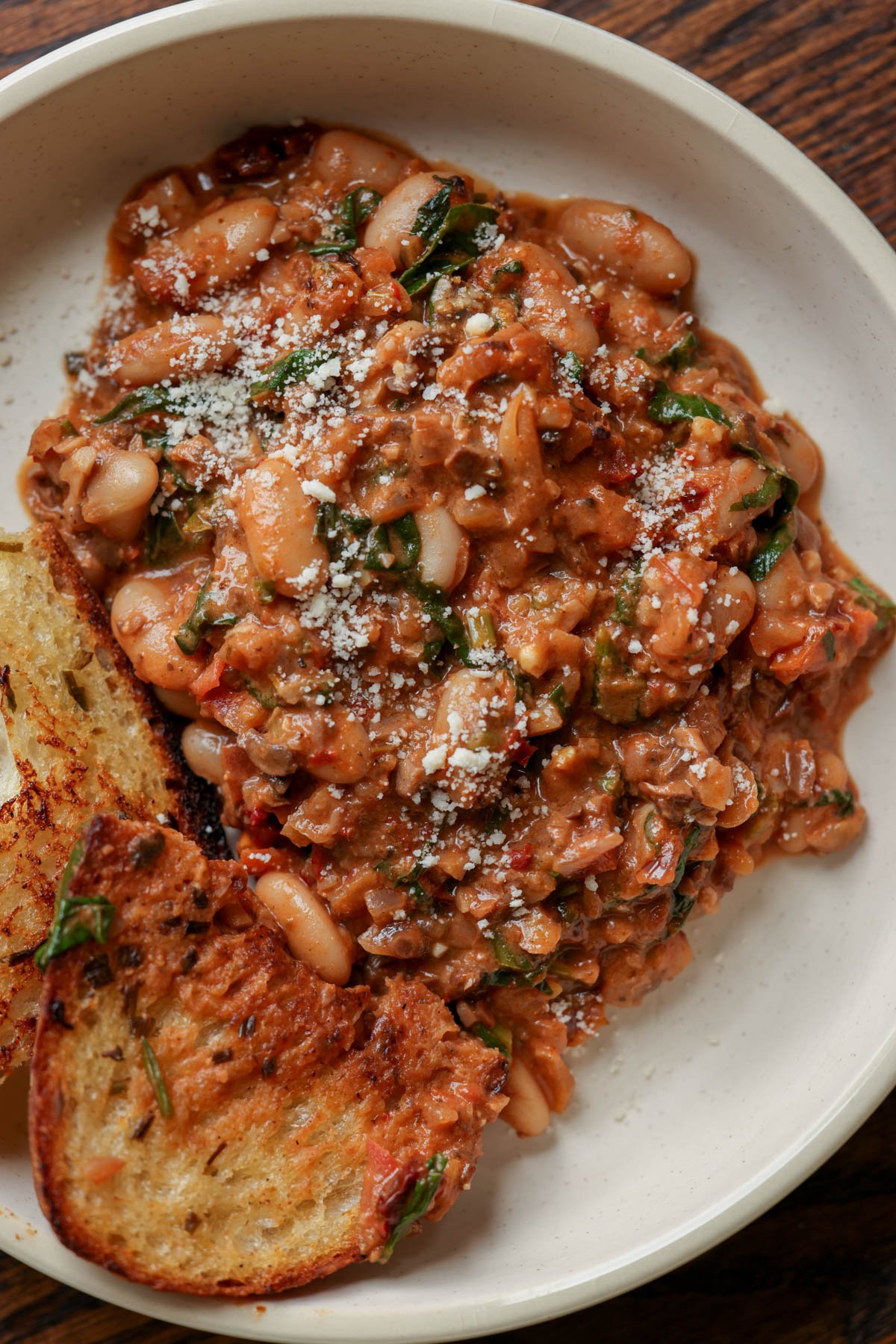 vegan sausage pasta sauce on a plate with toasted sourdough on the side