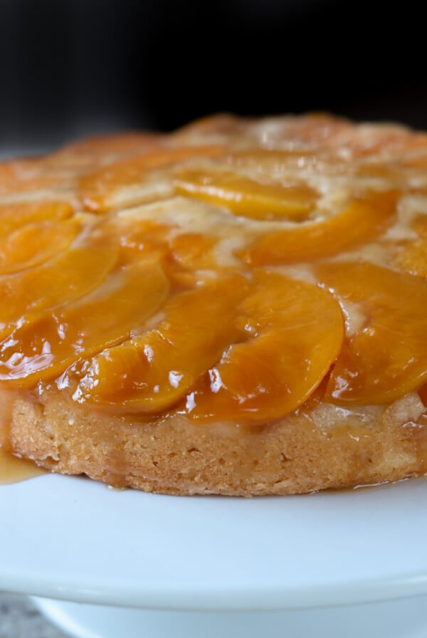 peach upside-down cake on a white cake stand