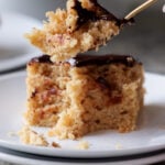 fork taking a bite of slice of peanut butter cake with chocolate peanut butter glaze