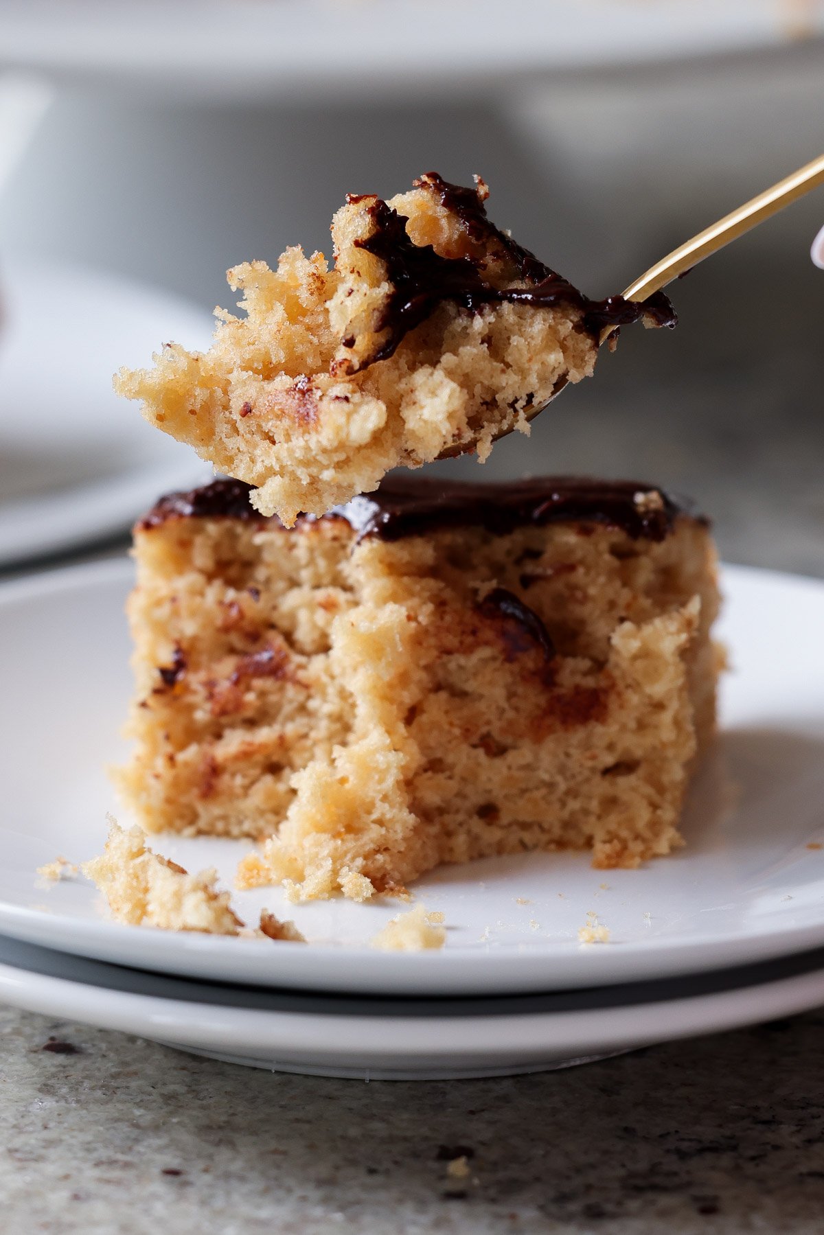 fork taking a bite of slice of peanut butter cake with chocolate peanut butter glaze