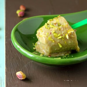 A pistachio kulfi icecream popsicle on a green plate