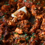 close-up of rara chicken curry in the pan with a piece of flatbread