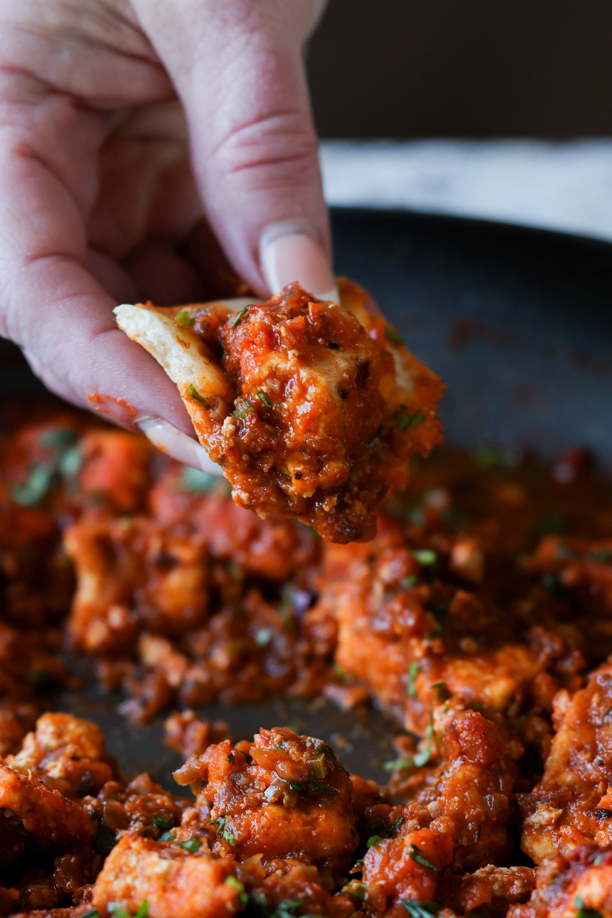 hand scooping up rara chicken curry with a piece of naan