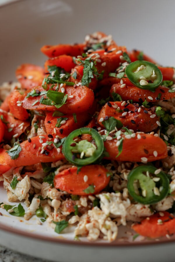 shredded tofu topped with roasted carrots in a bowl