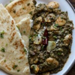 saag butter beans on a plate with flatbread on the side