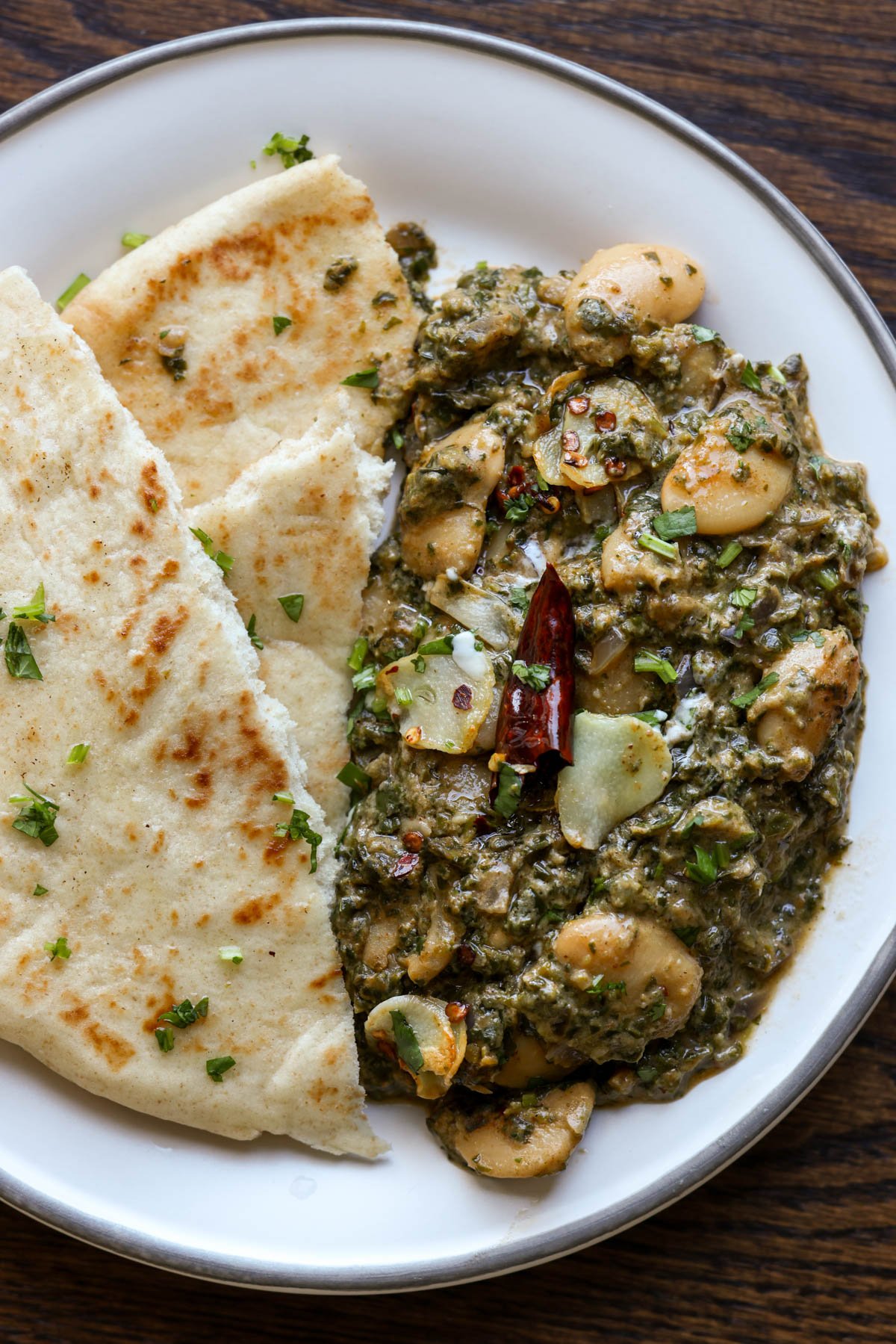 saag butter beans on a plate with flatbread on the side