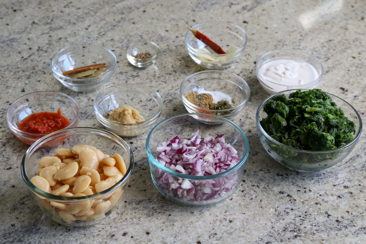 spinach, butter beans, and other saag ingredients in bowls on the counter