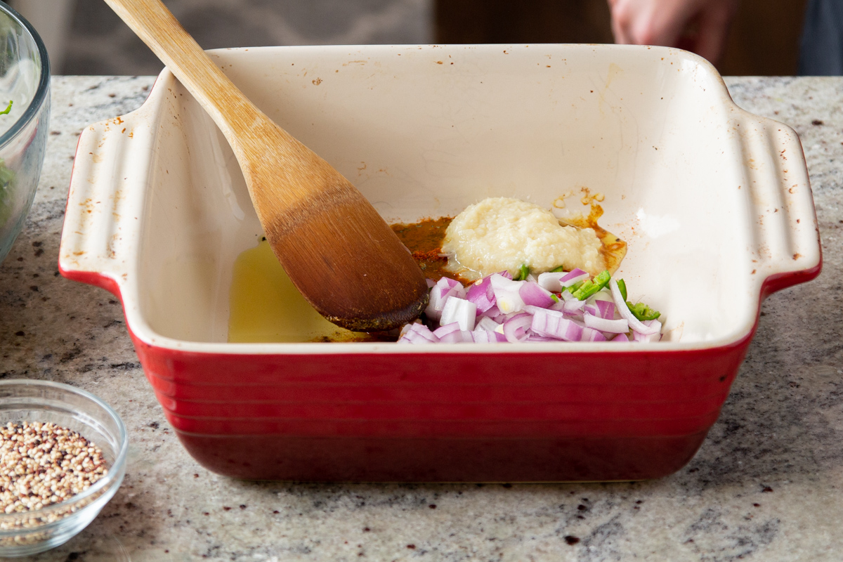 oil, spices, ginger and garlic in a red casserole dish 