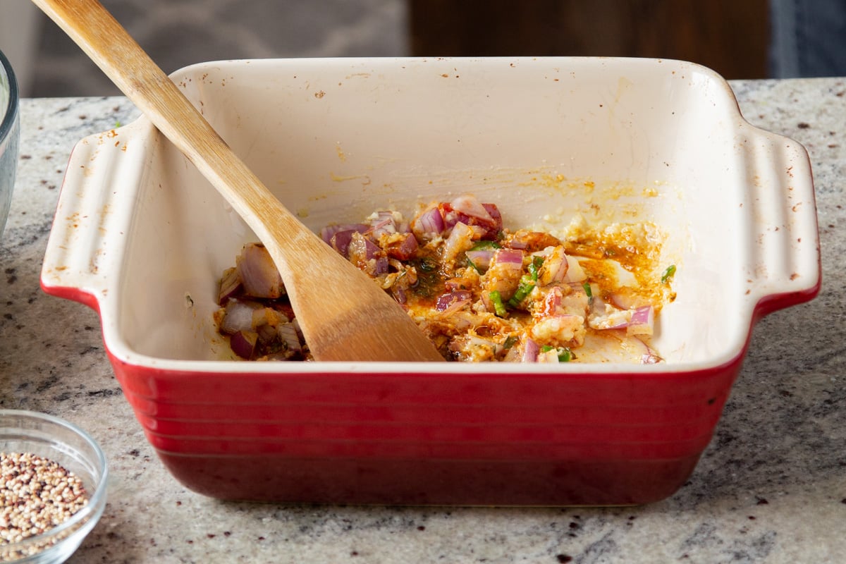 chopped onions and ginger with spices in a red casserole dish 