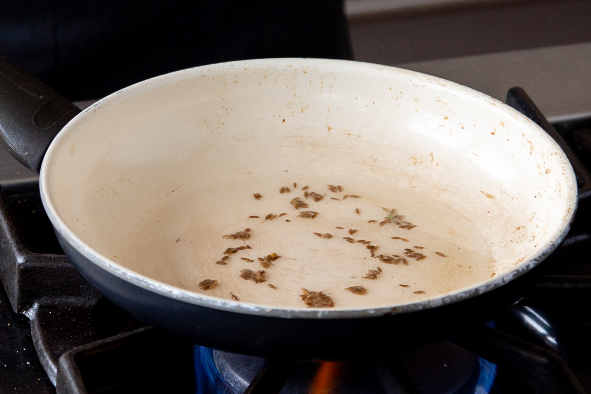 cumin seeds and oil in a frying pan 