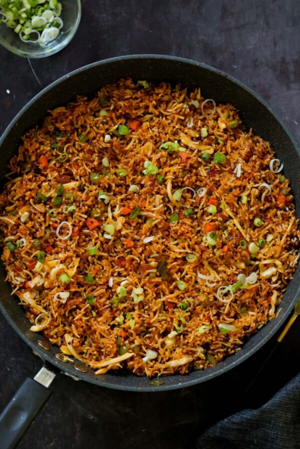 Schezwan fried rice in the pan with green onions for garnish