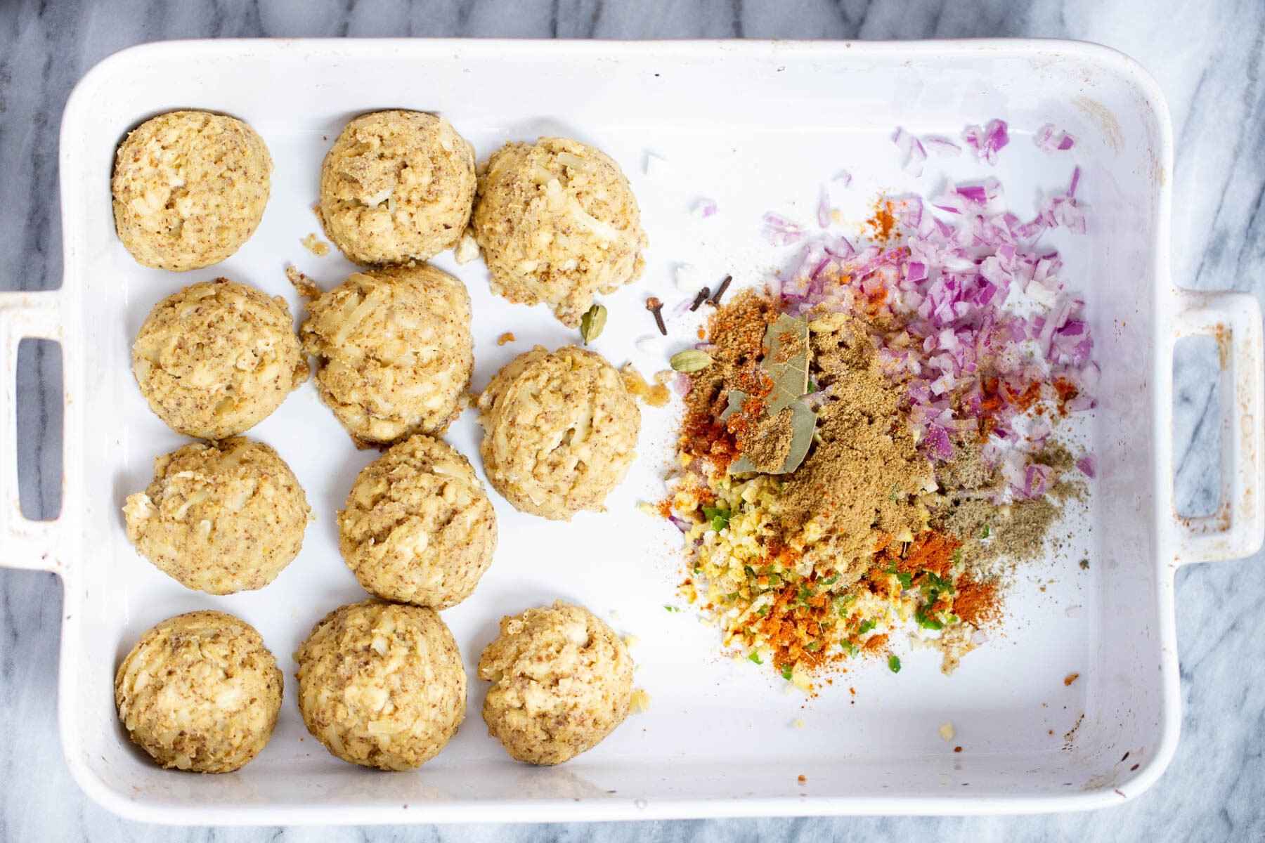 tofu koftas in a casserole dish with minced onion and spices