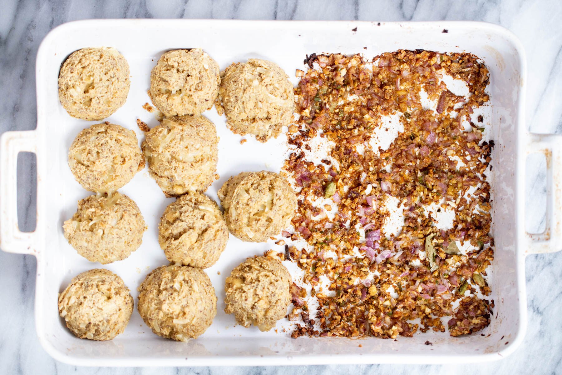 vegan koftas in a white casserole dish with onions, ginger and cili on the side