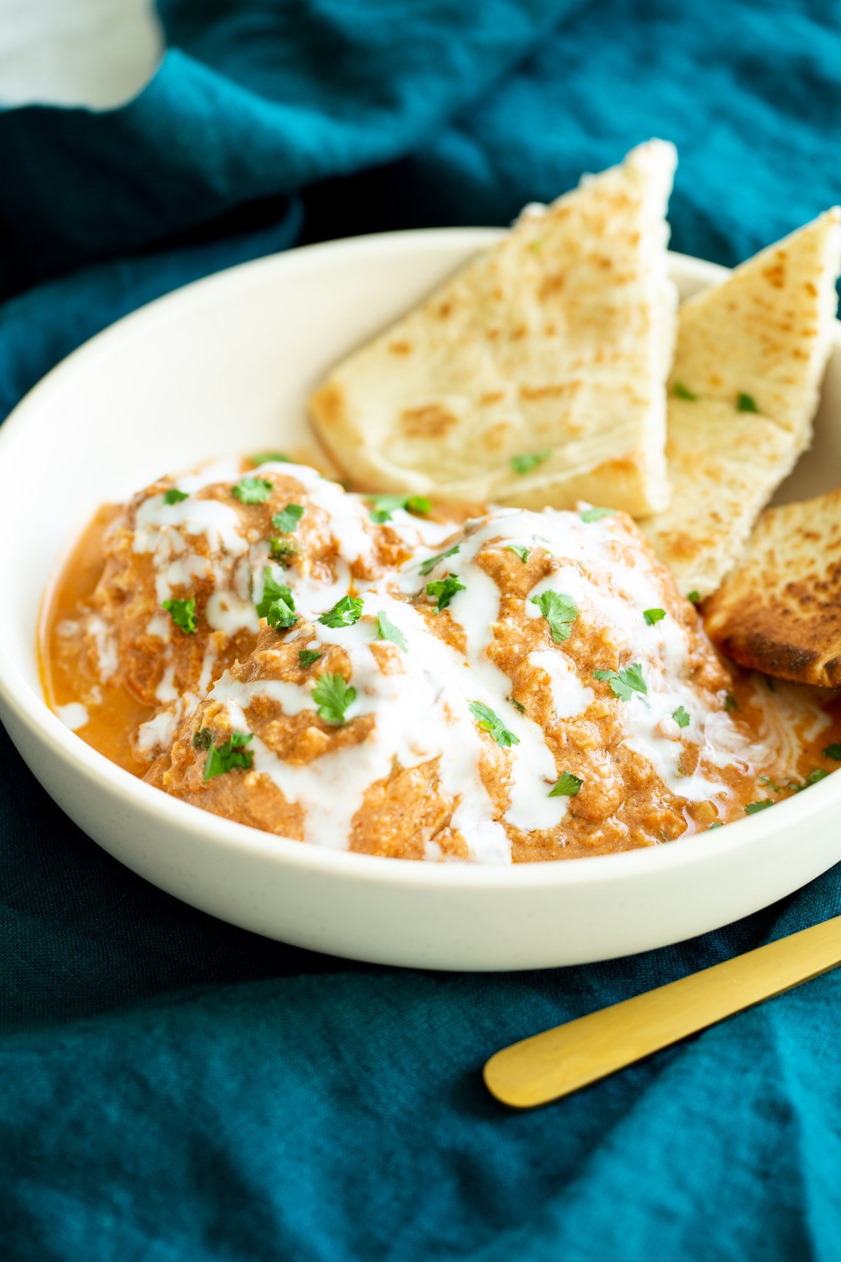 tofu kofta in creamy tomato sauce served in a white bowl drizzled with cashew cream