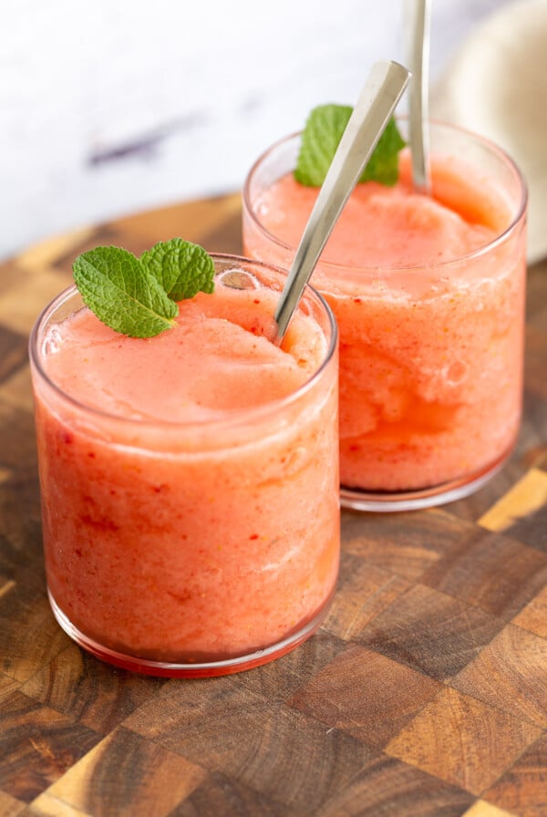 two glasses of vegan strawberry lemonade slushie with fresh mint leaves