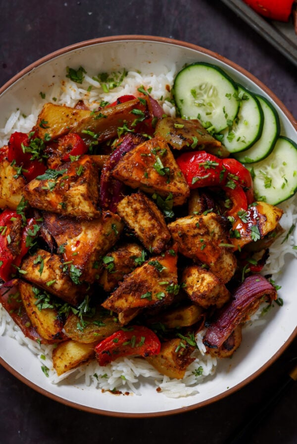 tofu tray bake in a bowl with rice and cucumber slices