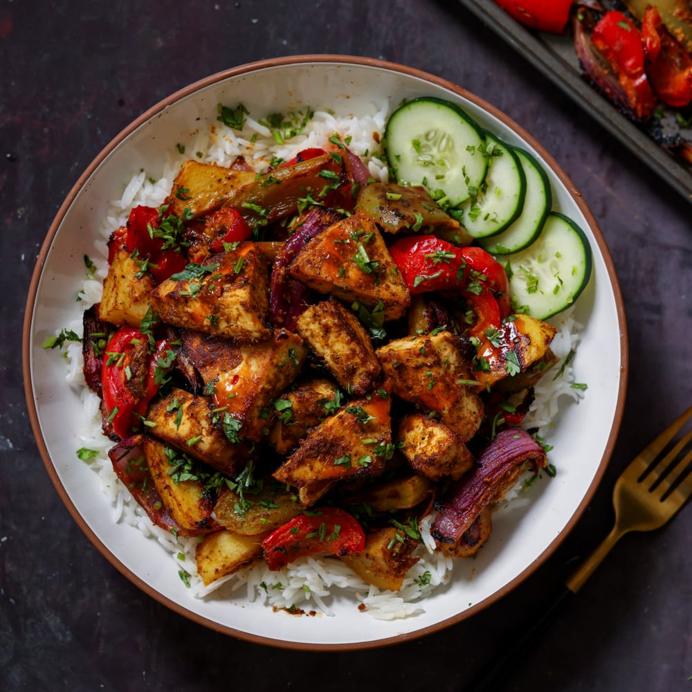 tofu tray bake in a bowl with rice and cucumber slices