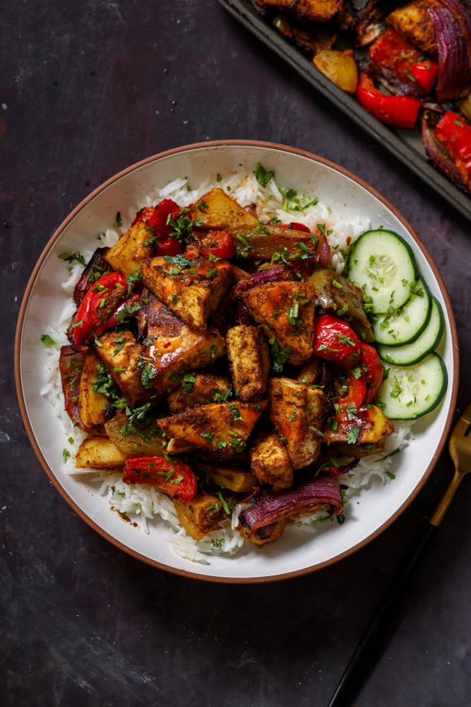 tofu tray bake in a bowl with rice and cucumber slices