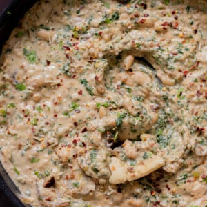 close-up of a panful of Tuscan beans with a piece of flatbread dipped into it