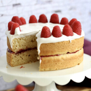 white vegan layer cake with vanilla icing and raspberries