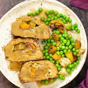 vegan holiday roast on a plate with gravy and vegetables