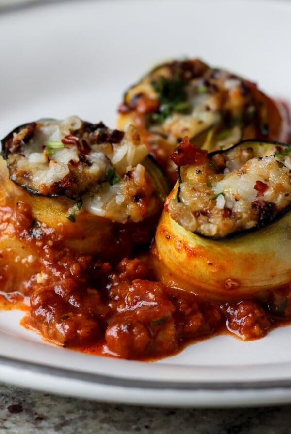 zucchini rolls on a white plate with tomato sauce